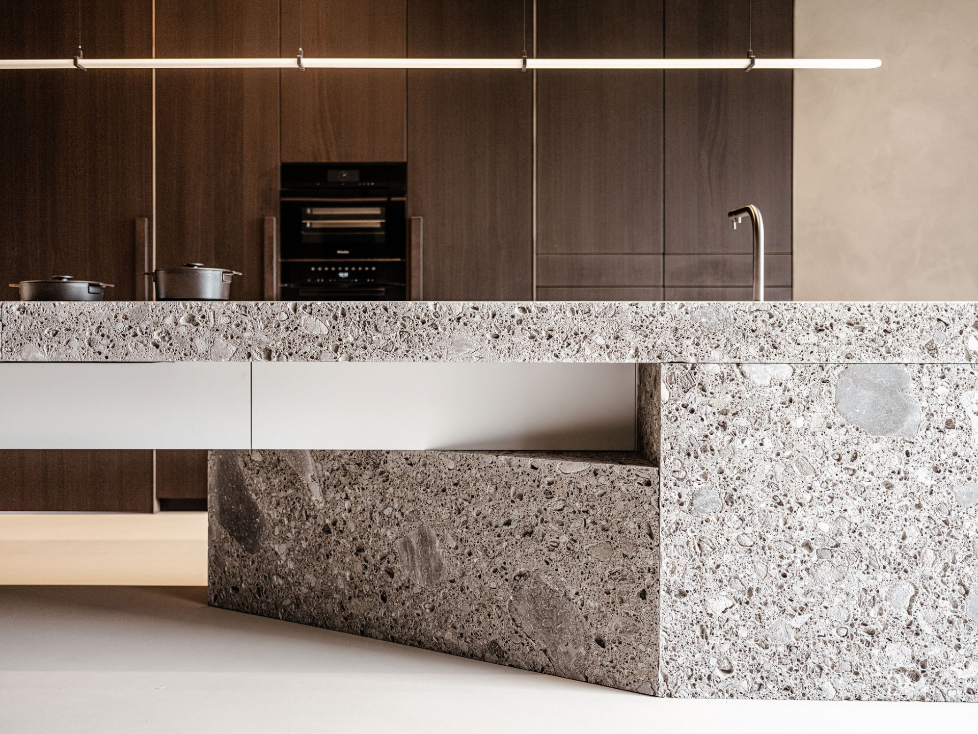 Kitchen island in natural stone with dark wood cabinetry in a House of Culimaat interior
